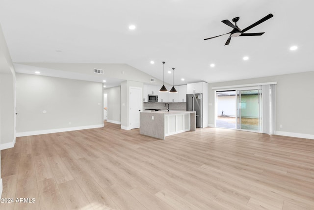 unfurnished living room featuring light wood-type flooring, vaulted ceiling, ceiling fan, and sink