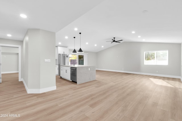 kitchen with white cabinets, decorative light fixtures, light wood-type flooring, and plenty of natural light