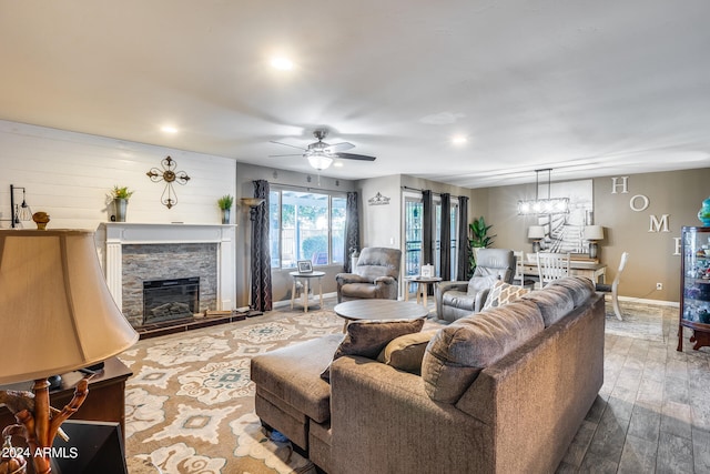 living room featuring ceiling fan, hardwood / wood-style flooring, and a stone fireplace