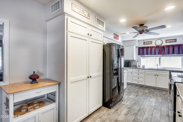 kitchen with white cabinets, black appliances, ceiling fan, and light hardwood / wood-style floors