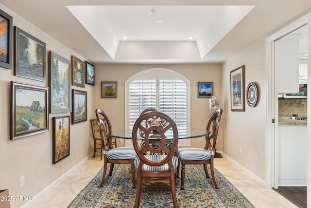 tiled dining space with a raised ceiling