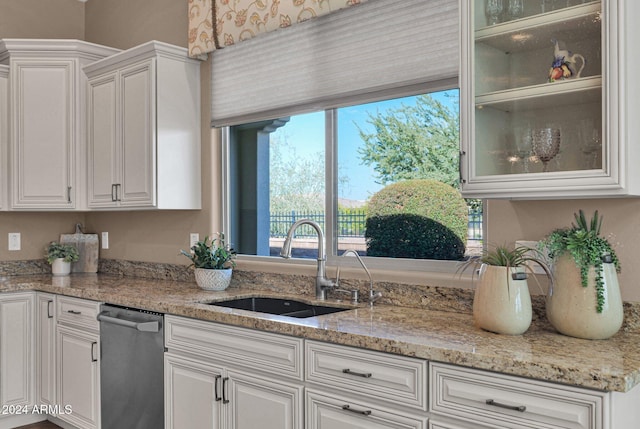 kitchen featuring white cabinetry, dishwasher, light stone countertops, and sink