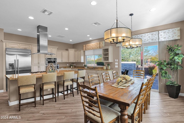 dining room with light wood-type flooring, an inviting chandelier, and sink