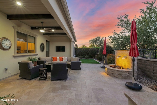 patio terrace at dusk with ceiling fan and an outdoor living space with a fire pit