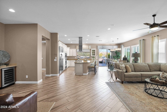 living room featuring ceiling fan, light hardwood / wood-style floors, sink, and beverage cooler