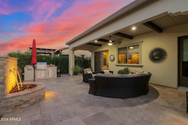 patio terrace at dusk with grilling area, an outdoor hangout area, ceiling fan, and exterior kitchen