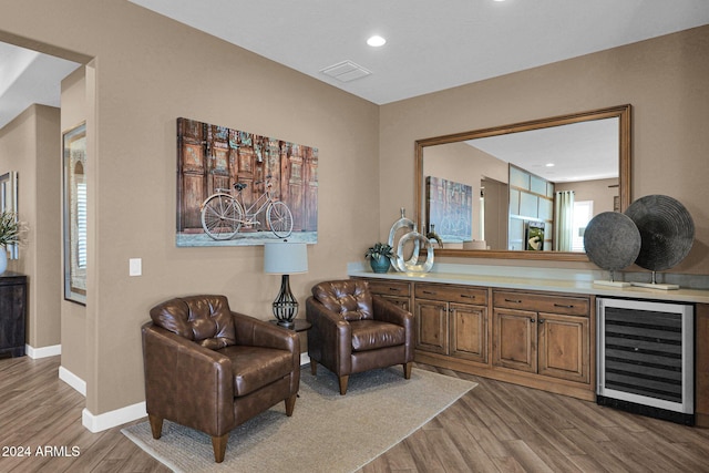 sitting room featuring bar area, light hardwood / wood-style floors, and beverage cooler