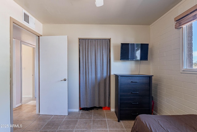 unfurnished bedroom with tile patterned floors and brick wall