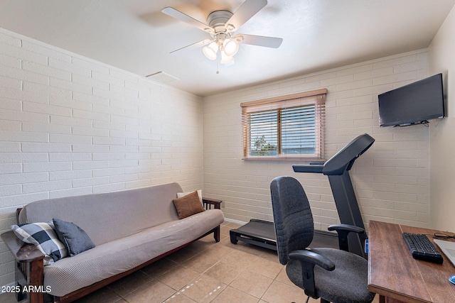 tiled home office with ceiling fan and brick wall