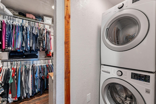 laundry area with dark hardwood / wood-style floors and stacked washing maching and dryer