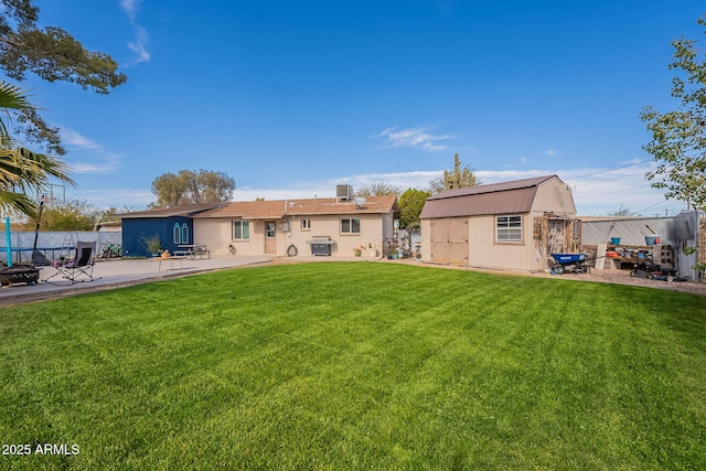 rear view of property with a storage shed, a patio area, and a lawn