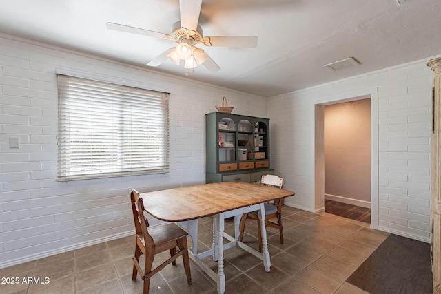 dining area featuring brick wall, dark tile patterned flooring, and ceiling fan