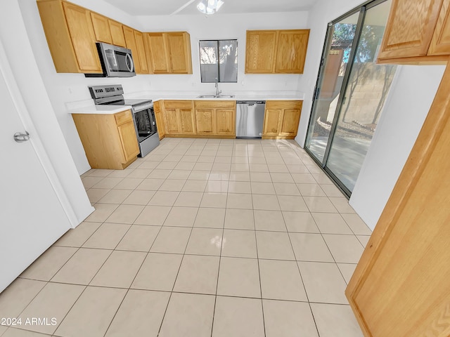 kitchen featuring light tile patterned floors, appliances with stainless steel finishes, sink, and a healthy amount of sunlight