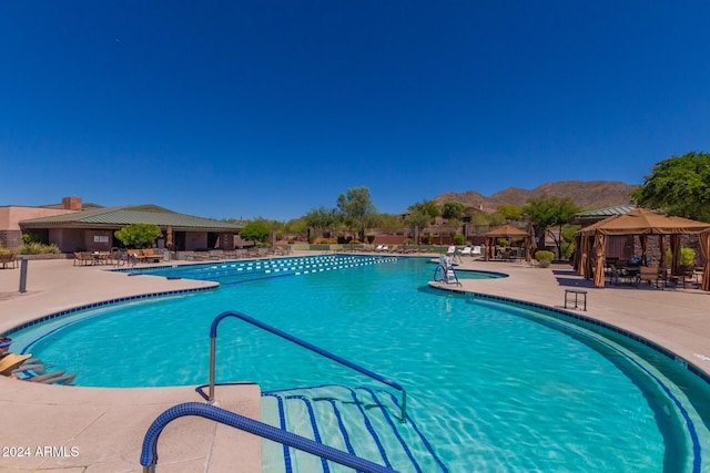 view of swimming pool featuring a patio, a mountain view, and a gazebo