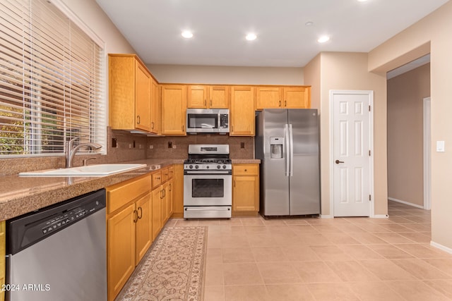 kitchen with stainless steel appliances, light tile patterned flooring, sink, and backsplash