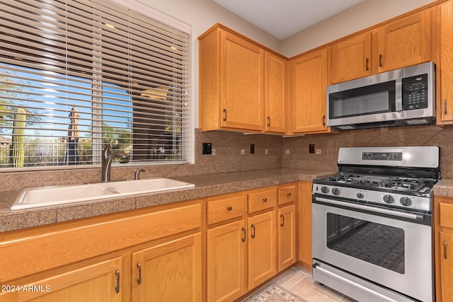 kitchen featuring decorative backsplash, appliances with stainless steel finishes, sink, and light tile patterned floors