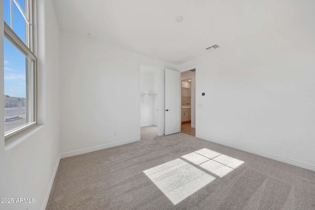 unfurnished bedroom featuring light colored carpet, a closet, and a walk in closet