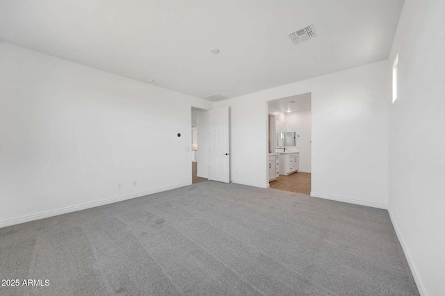 unfurnished bedroom featuring ensuite bathroom and light carpet