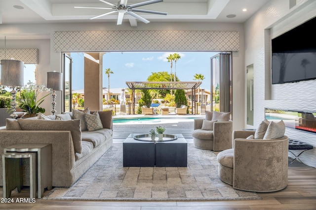 living room featuring ceiling fan, a tray ceiling, hardwood / wood-style floors, and a wealth of natural light