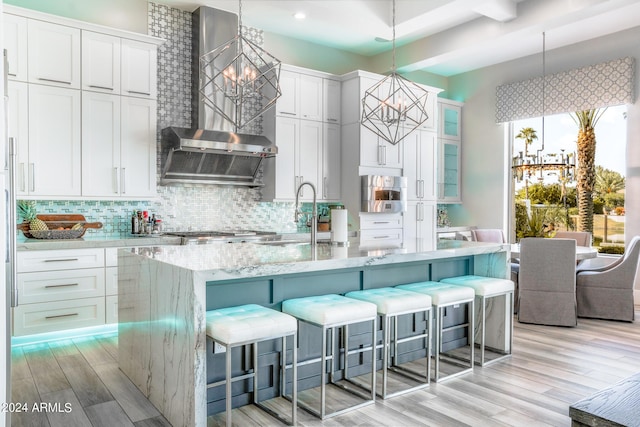 kitchen featuring pendant lighting, a center island with sink, white cabinets, and an inviting chandelier