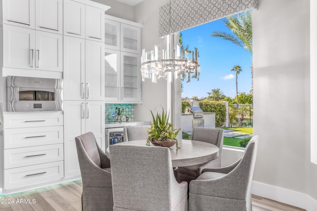 dining room with bar area, a chandelier, and light hardwood / wood-style flooring