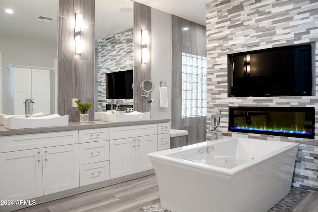 bathroom featuring vanity, a tub, wood-type flooring, and tile walls