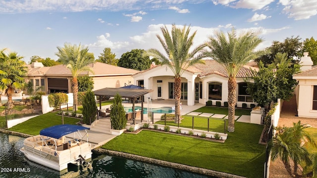 back of property with a water view, a lawn, and a patio area