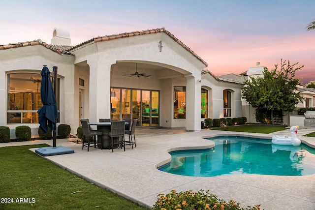 back house at dusk with ceiling fan and a patio