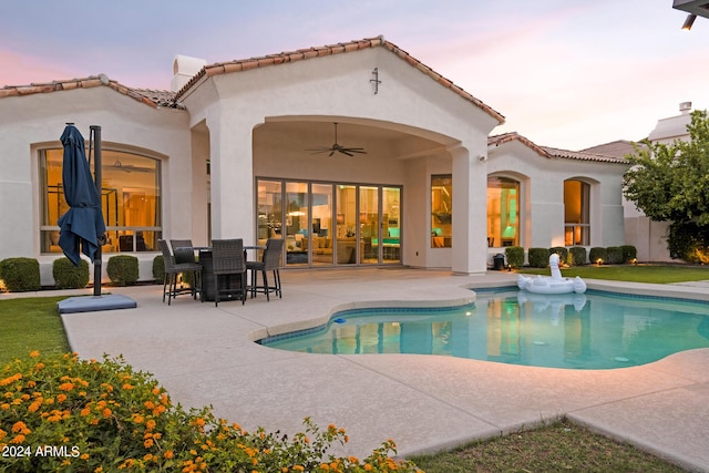 back house at dusk featuring a patio area and ceiling fan