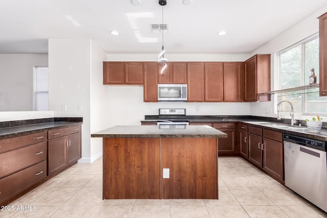 kitchen featuring sink, decorative light fixtures, a center island, light tile patterned floors, and appliances with stainless steel finishes