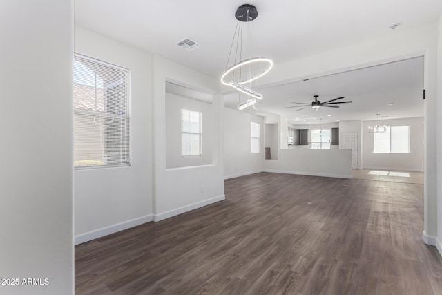 unfurnished living room featuring dark hardwood / wood-style flooring, ceiling fan with notable chandelier, and plenty of natural light