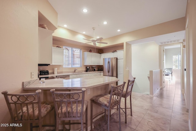 kitchen with appliances with stainless steel finishes, white cabinetry, sink, a breakfast bar area, and kitchen peninsula