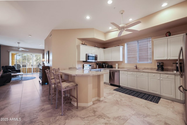 kitchen featuring sink, appliances with stainless steel finishes, a kitchen breakfast bar, white cabinets, and kitchen peninsula