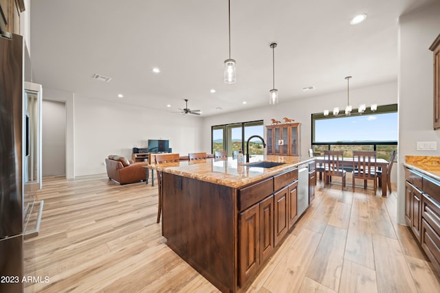 kitchen with light hardwood / wood-style floors, a center island with sink, sink, and stainless steel appliances