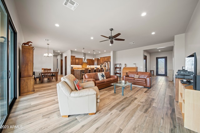 living room with ceiling fan with notable chandelier and light wood-type flooring