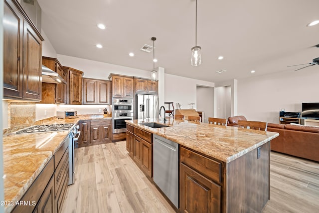 kitchen featuring pendant lighting, light hardwood / wood-style flooring, a large island with sink, sink, and stainless steel appliances