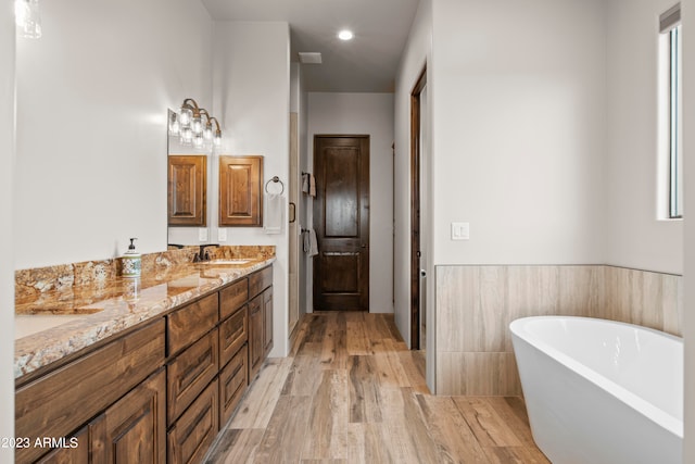 bathroom featuring wood-type flooring, vanity, and a bathtub