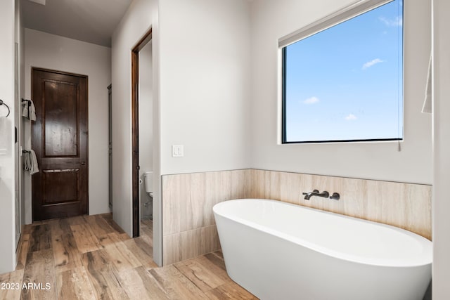 bathroom with hardwood / wood-style floors, toilet, and a tub