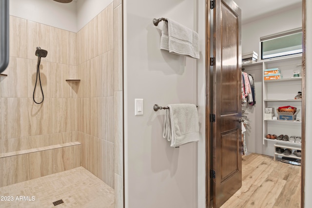 bathroom featuring wood-type flooring and a tile shower