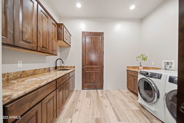 washroom featuring independent washer and dryer, light hardwood / wood-style floors, cabinets, and sink