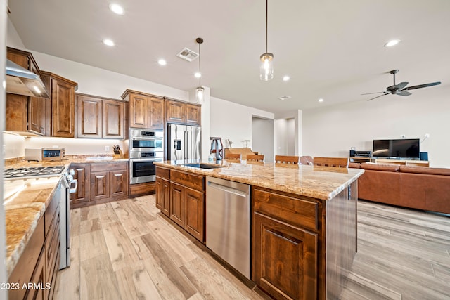 kitchen with a kitchen island, stainless steel appliances, sink, light hardwood / wood-style floors, and pendant lighting