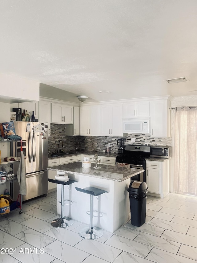 kitchen featuring a center island, stainless steel appliances, a kitchen breakfast bar, dark stone countertops, and white cabinets