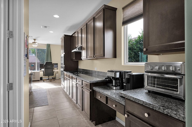 kitchen featuring dark brown cabinetry, light tile patterned floors, stainless steel appliances, and a wealth of natural light