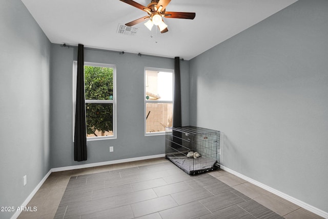 empty room with ceiling fan and light tile patterned floors