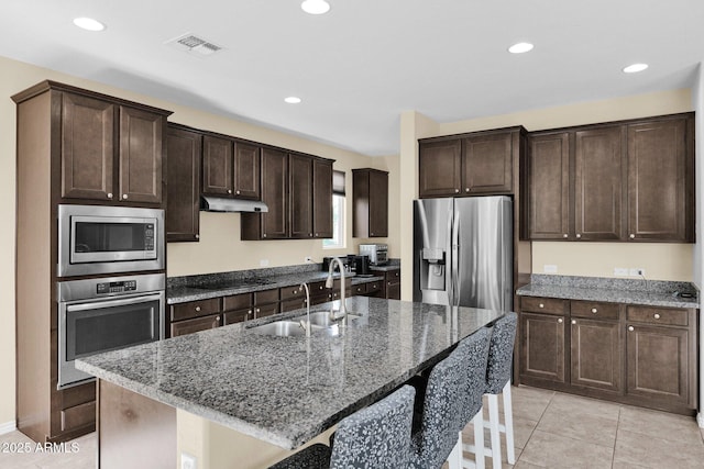 kitchen featuring sink, stainless steel appliances, a kitchen breakfast bar, a center island with sink, and light tile patterned flooring