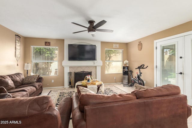 living area featuring ceiling fan, a fireplace, baseboards, and french doors