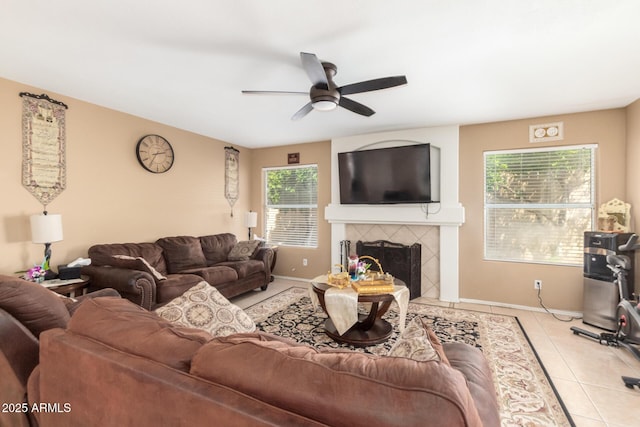 living area featuring ceiling fan, a fireplace, baseboards, and light tile patterned floors