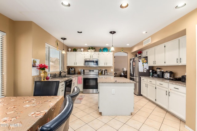 kitchen with arched walkways, stainless steel appliances, visible vents, white cabinets, and a sink