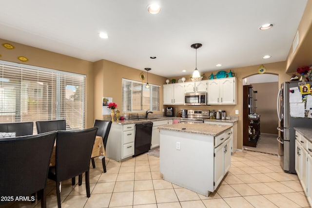 kitchen with a kitchen island, white cabinetry, stainless steel appliances, and light tile patterned flooring