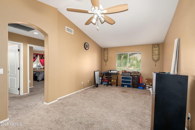 carpeted home office with arched walkways, lofted ceiling, visible vents, ceiling fan, and baseboards